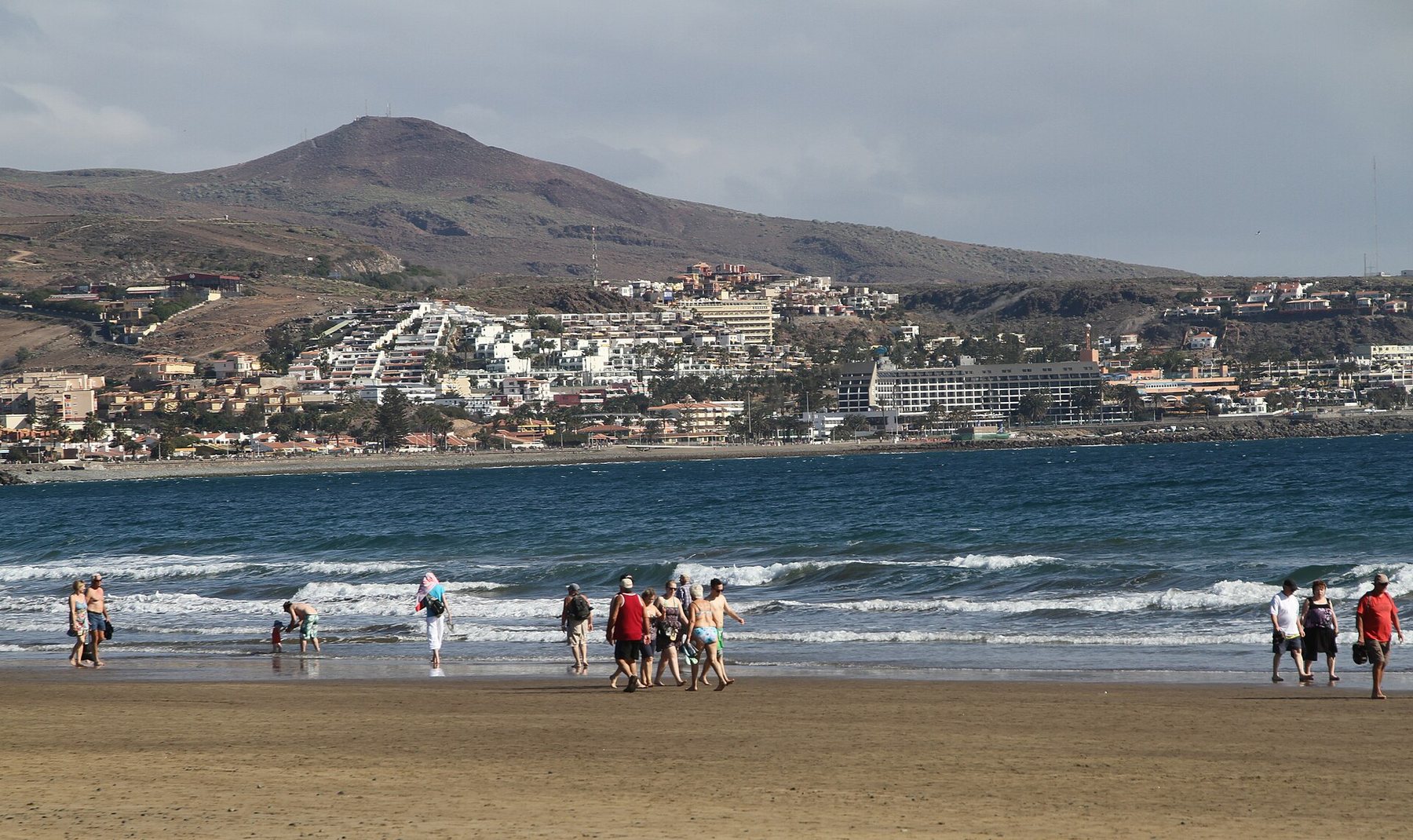 Stranden i Playa del Inglés med fjell og bebyggelse i bakgrunnen